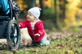 Baby boy playing in autumn forest with stroller, outdoors fun Royalty Free Stock Photo