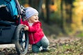 Baby boy playing in autumn forest with stroller, outdoors fun Royalty Free Stock Photo