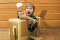 Baby boy playing with cardboard airplane on wooden wall background. Royalty Free Stock Photo