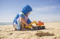 Baby boy playing on sand at the beach with excavator toy