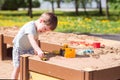 A baby boy plays with toys, cars in the sand on the playground. Kindergarten Royalty Free Stock Photo