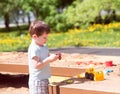 A baby boy plays with toys, cars in the sand on the playground. Kindergarten Royalty Free Stock Photo