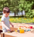 A baby boy plays with toys, cars in the sand on the playground. Kindergarten Royalty Free Stock Photo