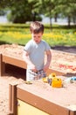 A baby boy plays with toys, cars in the sand on the playground. Kindergarten Royalty Free Stock Photo