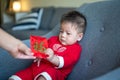 Baby boy receiving a red pocket envelope for Lunar New Year sitting on a sofa at home Royalty Free Stock Photo