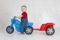 Baby boy riding his plastic scooter and trailer Royalty Free Stock Photo