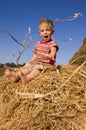 Baby boy sit on a hayrick Royalty Free Stock Photo