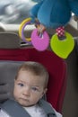 Baby boy sitting in child car seat with rattle hanging from ceiling Royalty Free Stock Photo