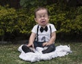 Baby boy sitting in a garden crying Royalty Free Stock Photo