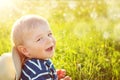 Baby boy sitting in grass on the fieald with dandelions