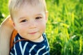 Baby boy sitting in grass on the fieald with dandelions