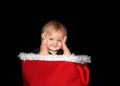 Baby boy sitting in red basket with fur lining holding sides of head smiling Royalty Free Stock Photo