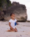 Baby boy sitting on sandy beach, holding toy car. Warm sunny day. Happy childhood. Summer vacation at the sea. Spending time near Royalty Free Stock Photo