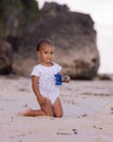 Baby boy sitting on sandy beach, holding toy car. Warm sunny day. Happy childhood. Summer vacation at the sea. Spending time near Royalty Free Stock Photo