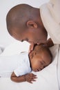 Baby boy sleeping peacefully on couch with father kissing head Royalty Free Stock Photo