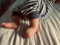 Baby boy small feet, no socks, little toes, playing in bed, blue stripes pijamas Royalty Free Stock Photo