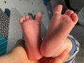 Baby boy small feet, no socks, little toes, playing in bed, blue stripes pijamas Royalty Free Stock Photo