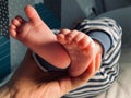 Baby boy small feet, no socks, little toes, playing in bed, blue stripes pijamas Royalty Free Stock Photo