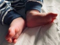 Baby boy small feet, no socks, little toes, playing in bed, blue stripes pijamas Royalty Free Stock Photo