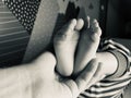 Baby boy small feet, no socks, little toes, playing in bed, blue stripes pijamas, black and white Royalty Free Stock Photo