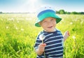 Baby boy standing in grass on the fieald with dandelions Royalty Free Stock Photo