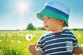 Baby boy standing in grass on the fieald with dandelions Royalty Free Stock Photo