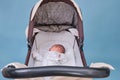 Baby boy in a stroller on a blue background. A child in white clothes in only diapers is lying in a stroller, studio shot Royalty Free Stock Photo