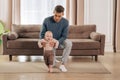 Baby boy taking his first steps with father's help at home Royalty Free Stock Photo