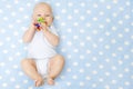 Baby Boy with Teether Toy In Mouth Lying over Blue Background, Happy