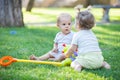 Baby boy and toddler girl playing while sitting on green grass Royalty Free Stock Photo