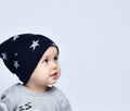 Baby boy toddler in grey casual jumpsuit, cap smiling and looking away over white wall background Royalty Free Stock Photo