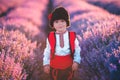 Baby boy in traditional Bulgarian folklore costume in lavender field. Working peasant during lavender harvest