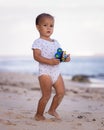 Baby boy walking on sandy beach, holding toy car. Warm sunny day. Happy childhood. Summer vacation at the sea. Spending time near Royalty Free Stock Photo