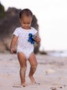 Baby boy walking on sandy beach, holding toy car. Warm sunny day. Happy childhood. Summer vacation at the sea. Spending time near Royalty Free Stock Photo