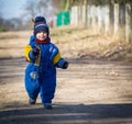 Baby boy walking by sandy rural road