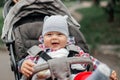 Baby boy in warm colorful knitted jacket sitting in modern stroller on a walk in a park. Child in buggy. Little kid in a Royalty Free Stock Photo