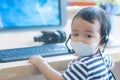 Baby Boy wearing facemask and headphone Playing Computer acting like call center officer or operator Royalty Free Stock Photo