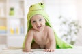 Baby boy wearing green towel in sunny bedroom. Newborn child relaxing after bath or shower. Royalty Free Stock Photo