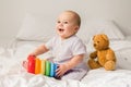 Baby boy in white bedroom. Newborn child in bed with toys. Nursery for children. Textile, pillows and bedding for kids