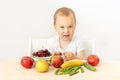 Baby boy 2 years old sitting at a table on a white isolated background and eating fruits vegetables, baby food concept, place for Royalty Free Stock Photo