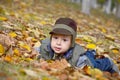 Baby boy among yellow fallen leaves