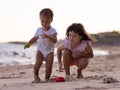 Baby boy and young girl playing with sand scoop and toy car. Brother and sister playing together on sandy beach near the sea. Royalty Free Stock Photo