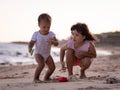 Baby boy and young girl playing with sand scoop and toy car. Brother and sister playing together on sandy beach near the sea. Royalty Free Stock Photo