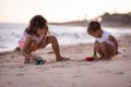 Baby boy and young girl sitting on sandy beach near the sea, playing with sand scoop and toy car. Brother and sister playing Royalty Free Stock Photo