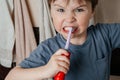 Baby brushes his teeth with an electric brush and smiles with an evil smile into the camera. Portrait close up Royalty Free Stock Photo