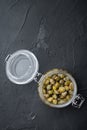 Baby capers in glass jar, on black background, flat lay with copy space for text