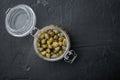 Baby capers in glass jar, on black background, top view with copy space for text