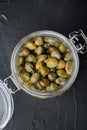 Baby capers in glass jar, on black background, top view