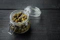 Baby capers in marinate glass jar, on black wooden background with copy space for text