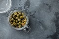 Baby capers in marinate glass jar, on gray background, top view with copy space for text